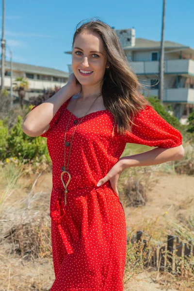 Brunette in het rood op een strand — Stockfoto