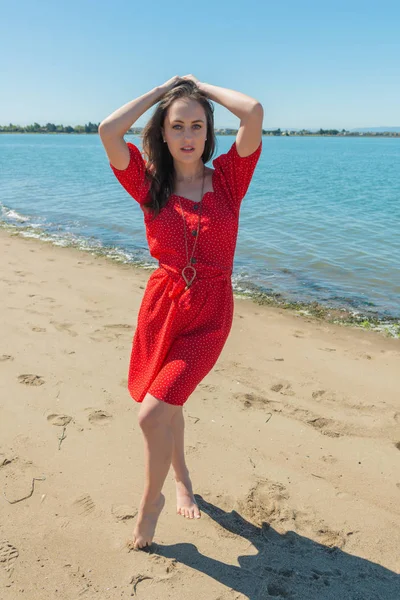 Brunette in het rood op een strand — Stockfoto