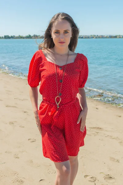 Brunette i rødt på en strand – stockfoto