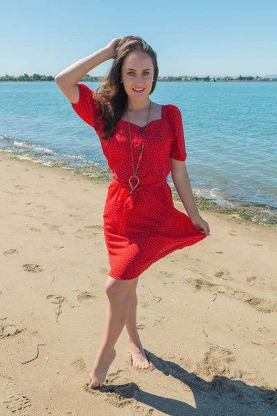 Brunette in het rood op een strand — Stockfoto