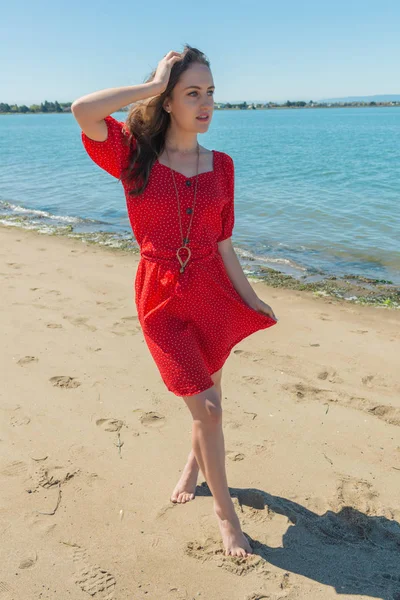 Brunette in red on a beach — Stock Photo, Image