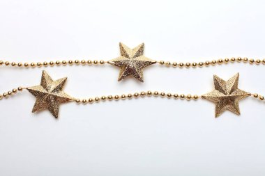 Altın yıldız ve boncuklu çelenk beyaz sırtüstü. Düz yatıyordu. Üst görünüm.