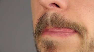 bıyıklı adam yalıyor dudaklarını dil tarafından iki kez, yan görünüm, closeup makro 