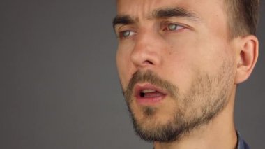 sakallı adam portresi öksürük ve onun yumruk, yan görünüm, gri arka plan ile ağzını kapatır