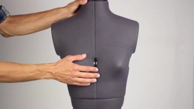 bir plastik cerrah değiştirmek gibi ayar vidası, önden görünüm gri arka plan sıkma bir kadın dikiş manken üzerinde meme boyutunu el terzi