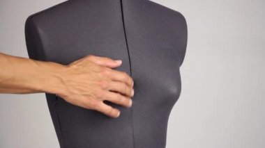 bir plastik cerrah artırmak gibi yan görünümü gri arka plan ayarlama vida sıkma bir kadın dikiş manken üzerinde meme boyutunu el terzi