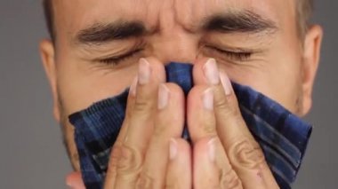 adam burnunu ve mendil burun bir mavi mendil, yüz closeup, gri arka plan, ön görünüm ile sakal ve bıyık darbeler ile