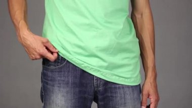 Yeşil tişörtlü adam yeni prezervatif kot açık cebinden dışarı alır ve yukarı, güven ve sorumluluk, gri arka plan üzerinde dayalı ilişkiler kavramı parmak hareketi yapar