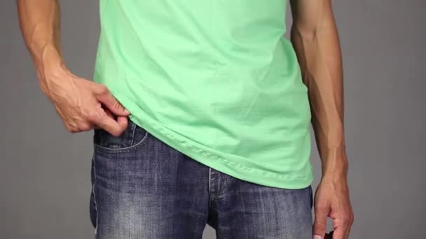 穿绿色衬衫的男子从蓝色牛仔裤的前口袋里拿出新的避孕套 做手势大拇指 基于信任和责任的关系概念 灰色背景 — 图库视频影像