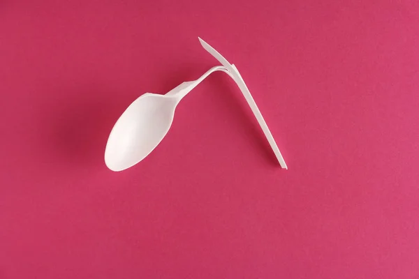 Sola cuchara de plástico desechable blanco roto sobre fondo rosa , — Foto de Stock