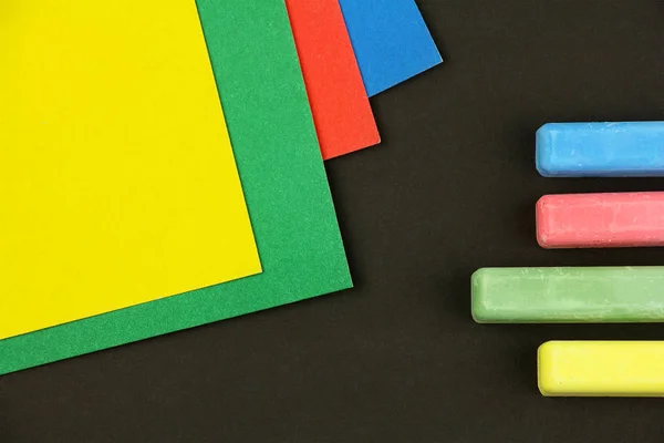 Cuatro crayones de colores para niños y papeles sobre fondo negro , — Foto de Stock