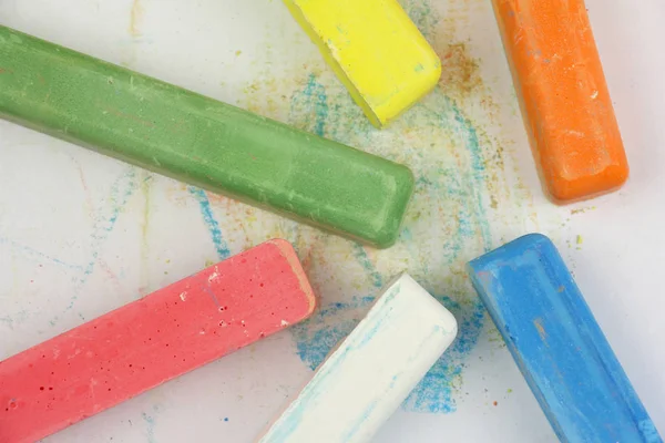 Crayones de colores para niños esparcidos en papel blanco, vista superior — Foto de Stock