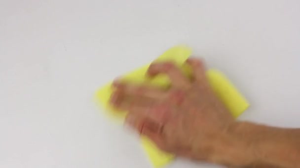 人間の手は黄色の正方形の布でテーブルの白い表面を注意深く拭く — ストック動画