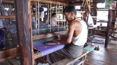 Inle Lake, Myanmar - 14 Kasım 2014: Inle gölünde dokuma fabrikası. Vintage mekanik dokuma tezgahı üzerinde çalışan yerel bir adam (arka görüş tarafı)