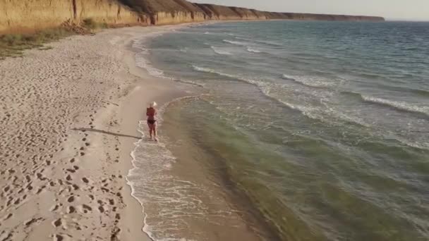 Дівчина Бікіні Білому Капелюсі Дитиною Руках Ходить Уздовж Узбережжя Піщаному — стокове відео