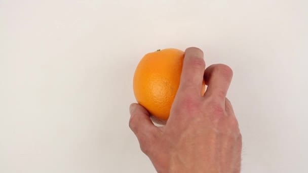 男性の手は白いテーブルに熟したオレンジを置き すぐに果物をねじり クローズアップ — ストック動画