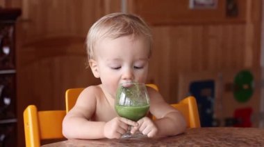 Bebek çocuk kendi başına şarap kadehinden taze yeşil smoothie içecekler. Sağlıklı vegan/ham yaşam tarzı.