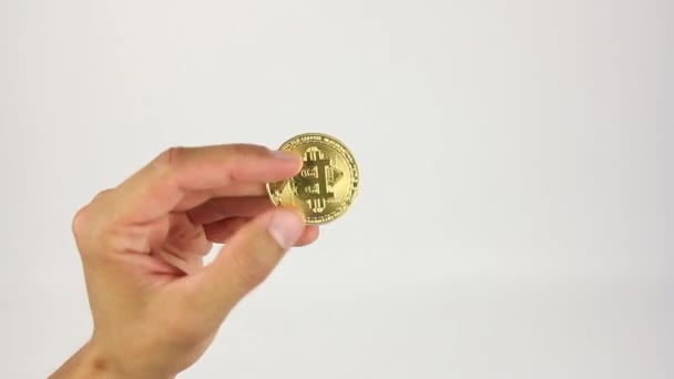 Mão Humana Gira Moeda Ouro Bitcoin Entre Dedos Fundo Branco — Vídeo de Stock