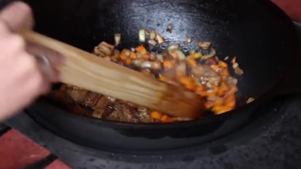 人的手搅拌煮沸的油和肉与木桨 准备皮拉夫 右视图 — 图库视频影像