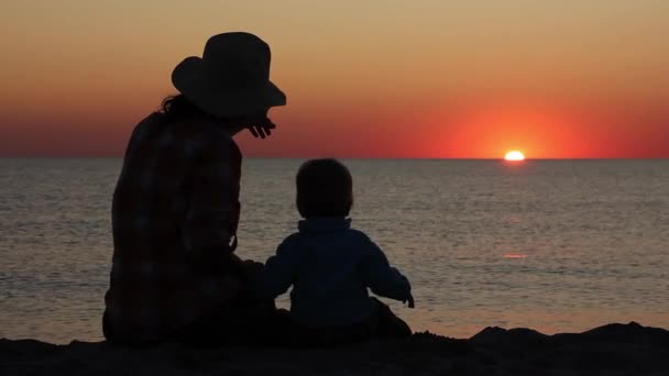 日没時の海の背景に母と赤ちゃんのシルエット — ストック動画