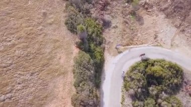 bisiklet, çalılar, çiftlik arazisi ve kayalık sahil, Kıbrıs'ta seyahat aile tarafından eski asfalt yolda çocuk sürmek ile iki bisikletçi turist havadan görünümü