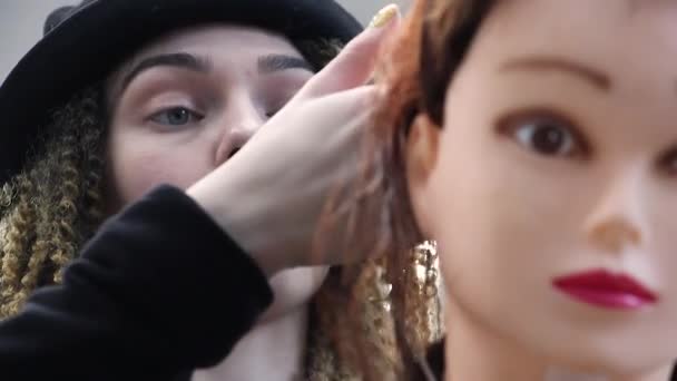 미용사는 마네킹 머리에 새로운 기술을 마네킹에 스타일리스트 얼굴에서 카메라 초점을 — 비디오