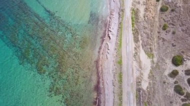 deniz kıyısı, deniz ve çalılar ile eski asfalt yol havadan görünümü, Kıbrıs'ta seyahat, statik kamera 
