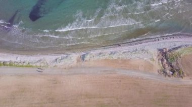 bisikletle eski toprak yolda deniz kıyısına yakın çocuk sürmek ile iki bisikletçi turistlerin havadan görünümü, Kıbrıs'ta seyahat aile, drone statik kamera, çerçevenin solundan sağa hareket