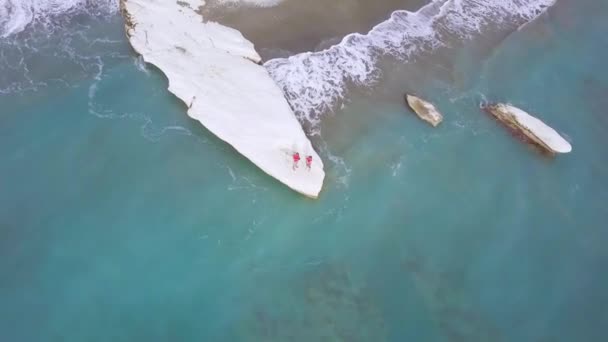 在塞浦路斯卡利姆诺斯或总督海滩的白色石披上的家庭娱乐鸟瞰图 父亲和儿子在海岸上穿红色衬衫 人们旅行 无人机相机飞来飞去 — 图库视频影像