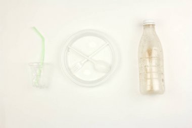 kullanılan kirli plastik tek kullanımlık sofra, plaka çatal kaşık şişe bardağı ve saman, beyaz arka plan, çöp veya kirlilik çevre sorunu kavramı