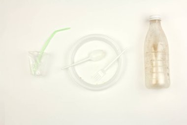 kullanılan kirli beyaz plastik tek kullanımlık sofra, plaka çatal kaşık şişe fincan ve saman, beyaz arka plan, parti sonrası kirli bulaşıklar, kirlilik ve çevre sorunu