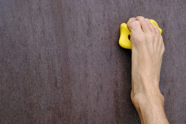 Derecho humano descalzo como una mano sostiene en amarilla escalada bodega en pared de escalada artificial, concepto de diversión y el deporte de la alegría, espacio de copia de primer plano — Foto de Stock