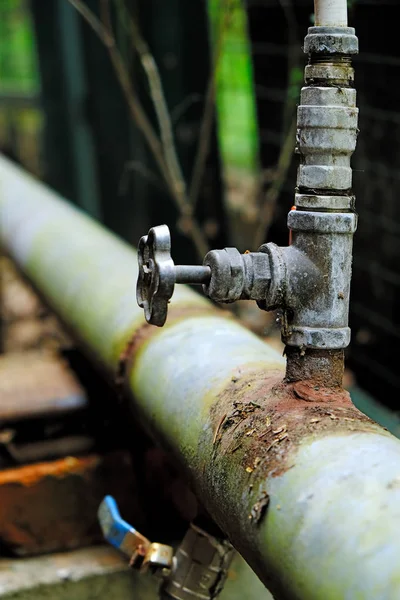 Velha conexão enferrujada de dois tubos de água com torneira do tubo principal para o jardim local, conceito de desgaste de tubos — Fotografia de Stock