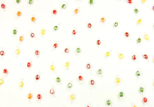 Sok színes cukorka véletlenszerűen szétszórva fehér alapon, fogalma szórakoztató gyermek party, vagy születésnapi — Stock Fotó
