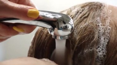 stilist nazikçe müşteri saç başlığından şampuan köpük yıkar, kuaför atölyesinde eğitim, yakın çekim 