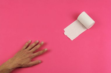 pembe arka plan ve insan eli üzerine beyaz tuvalet kağıdı almaya çalışın, yakın çekim, kopyalama alanı, mide sorunları kavramı