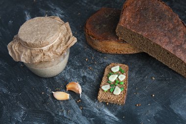 Bir parça taze zanaatkar ekmeği soğan soğanı ve karanfil sarımsağı, cam kavanozda mayalı ekmek ve sade bir çavdar ekmeği, mayasız tahılsız ekmek sağlıklı vejetaryen atıştırmalığı.