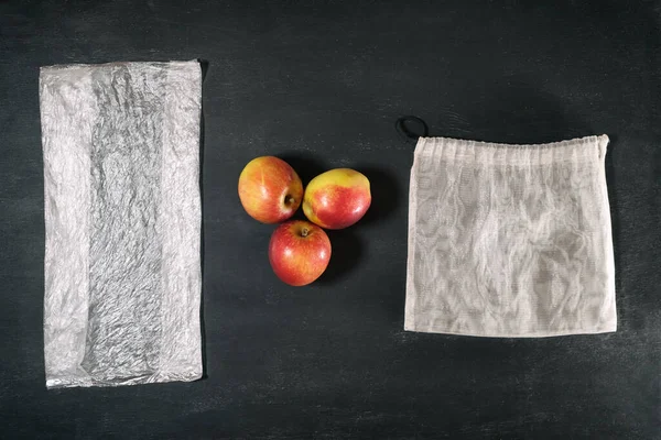 使い捨てのプラスチックパッケージと再利用可能なトレンディーなエコ食料品メッシュ 意識的な消費主義 廃棄物ゼロ 環境汚染の概念の間で3つの新鮮なリンゴを選択します — ストック写真