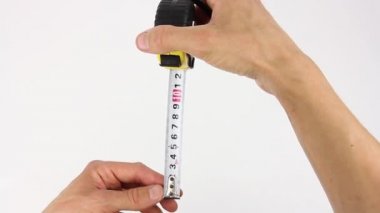 İnsan elleri mezuradan mezurayı çıkarır ve boyutları, genişliği, yüksekliği ve köşegenleri ölçer, beyaz arkaplanda görünümü kapatır