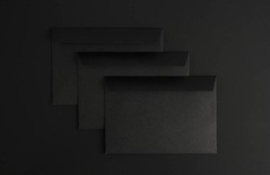 Siyah arkaplanda üç boş siyah zarf, kopyalama alanı olan harf modeli, toplam siyah 