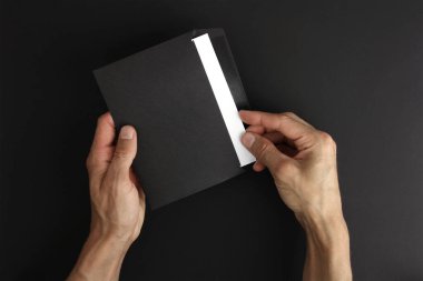 Siyah arka planda beyaz harfli boş bir zarf tutan erkek elleri, iyi bir mesaj alır ve okur, açık postalar, kopyalama alanı ile maket 