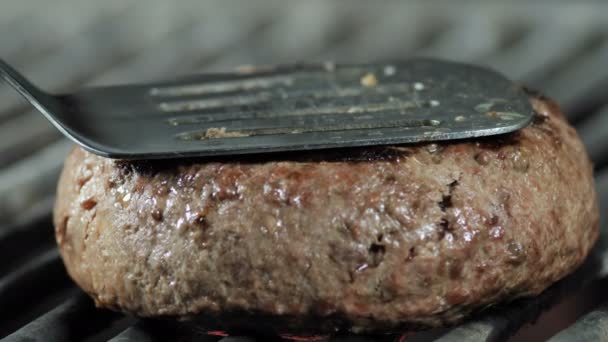 Patty carne semi-cozido é pressionado com uma espátula de ferro para a grelha para a plena prontidão, ingredientes para um hambúrguer — Vídeo de Stock