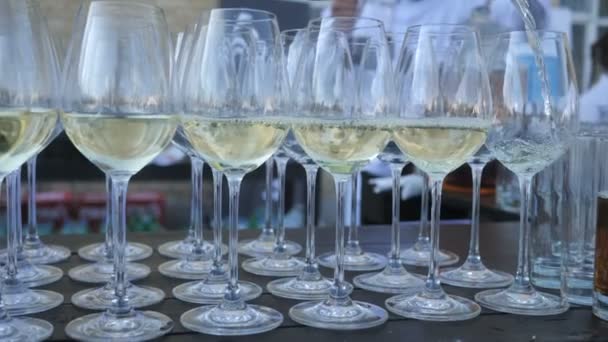 Fondo de un gran número de copas camarero vierte vino blanco italiano de una variedad de uva tradicional, recogido y hecho por el agricultor para la vinificación artesanal — Vídeo de stock