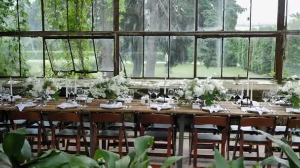 Het versieren van een feestelijke tafel. Versieren tafels met boeketten van natuurlijke verse bloemen met kaarsen en decor voor een bruiloft of een feestje voor een familiefeest — Stockvideo