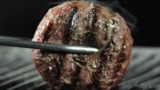 鉄のトングで、私はグリルの上に大きなジューシーな肉のパティをひっくり返す — ストック動画
