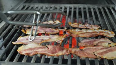 Pastırma dilimleri ızgara, kızarmış pastırma gelen pastırma drenaj yağ, demir maşa ile siyah eldiven şef ızgara bitmiş pastırma alır