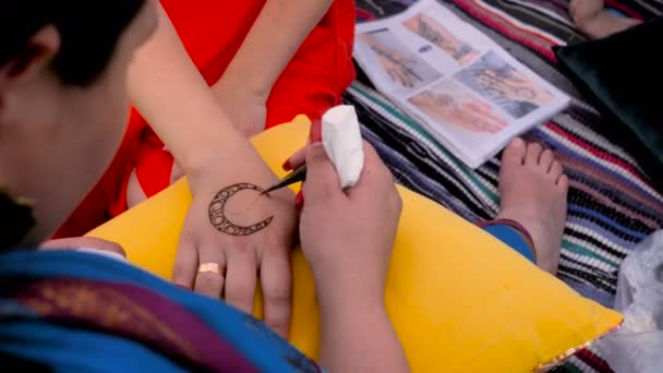 Processus d'application mehndi sur les mains féminines. Maître dessine un croissant de peinture Ralenti 4k — Video