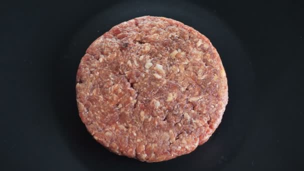 Круглий бургер обертається навколо своєї осі на ізольованому чорному тлі, котлета з яловичини або телятини, вид зверху — стокове відео