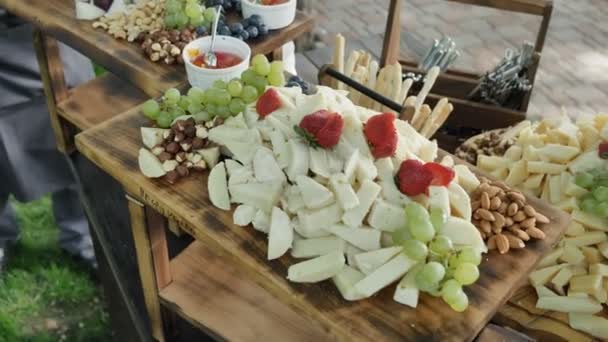 Catering service. Station with a large assorted cheese Cheddar, Gorgonzola, Brie, Gouda cheese, Parmesan, Feta, Ricotta, Maasdam, Emmental and Gruye. Decorated with Grapes, Strawberries, Nuts, Cashew — Stock Video