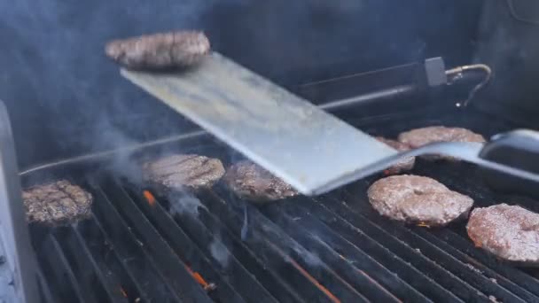 Chuleta de hamburguesa cocinada en una parrilla lanzada a la parte superior, aparece una llama.Cocinar hamburguesas y hamburguesas de queso en una llama de una carne de parrilla jusper de carne de cerdo ternera apisonada y filetes de pollo para una fiesta — Vídeos de Stock